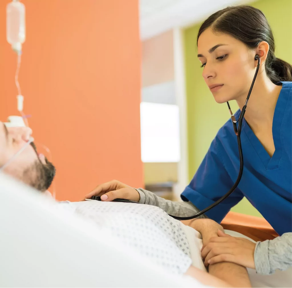 Femme médecin écoute le coeur de son patient allongé sur un lit d'hôpital